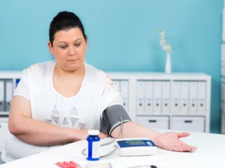 žena s nadváhou si měří tlak tlakoměrem