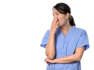 Exhausted attractive female doctor or nurse in blue scrubs standing