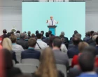 Mature doctor giving a speech on a stage at a conference in front of an audience