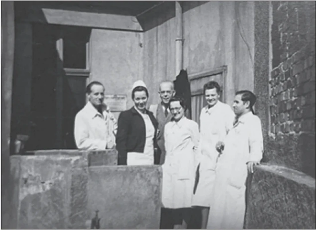 Zleva MUDr. Jiří Šimek, diplomovaná sestra Ludmila Šínová, prof. MUDr. Kamil Henner, Marie Kopáčková (sekretářka), MUDr. Libuše Fučíková a MUDr. František Pleskot na dvorku budovy českého neurologického oddělení Na Křižovatce 481 (dnes Viničná 9) (1945). (zdroj: MÚA AV ČR, fond Kamil Henner ml.) Fig. 5. From left: Jiří Šimek, MD; Ludmila Šínová, registered nurse; Prof. Kamil Henner, MD; Marie Kopáčková, secretary; Libuše Fučíková, MD; and František Pleskot, MD, in the courtyard of the Czech neurological ward building at Na Křižovatce 481, now Viničná 9 (1945).  (source: MIA CAS, collection Kamil Henner Jr.