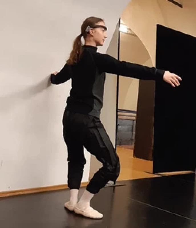 Studentka Katedry tance HAMU provádějící prvek plié s EEG měřicím přístrojem Muse.</br> Fig. 3. Student of the Dance departement of Music Academy of Performing Arts in Prague performing a plié with EEG device Muse.