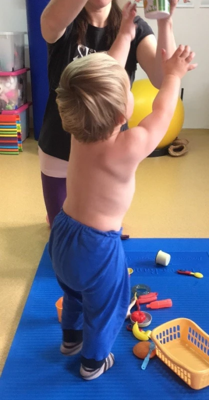 Věk 2,5 roku, úchop předmětu ve vzpažení, patrný větší souhyb lopatky do abdukce a zevní rotace, než je odpovídající rozsahu pohybu do flexe v rameni PHK, stále lehce vázne supinace předloktí.<br>
Fig. 10. Age 2,5 years, grip of the subject in elevation of upper arm, noticeable more movement of the scapula into abduction and external rotation than is the corresponding range of motion in flexion in the shoulder right upper limb, still slightly falters supination of the forearm